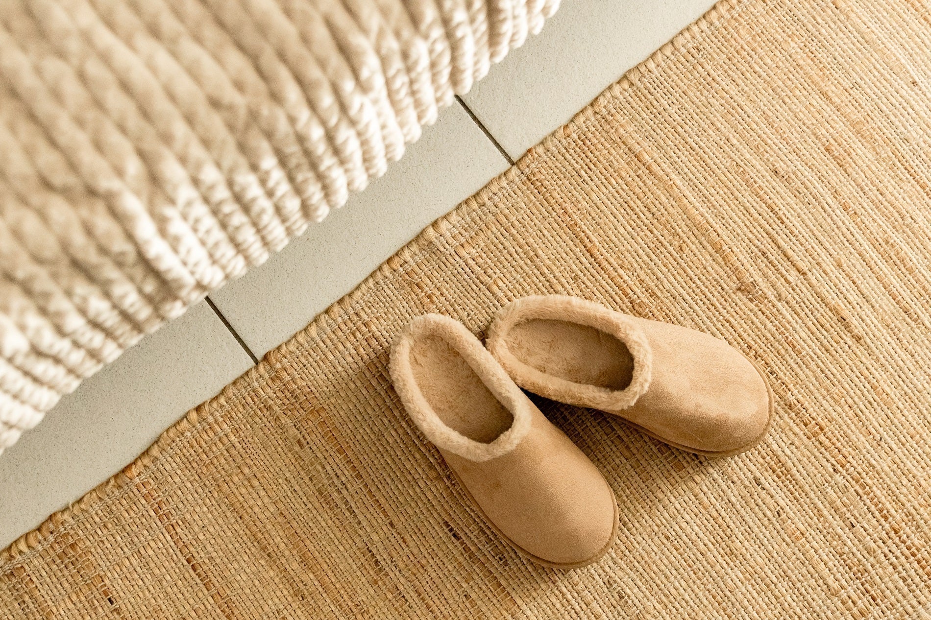 Pair of Ugg slippers at the foot of a bed