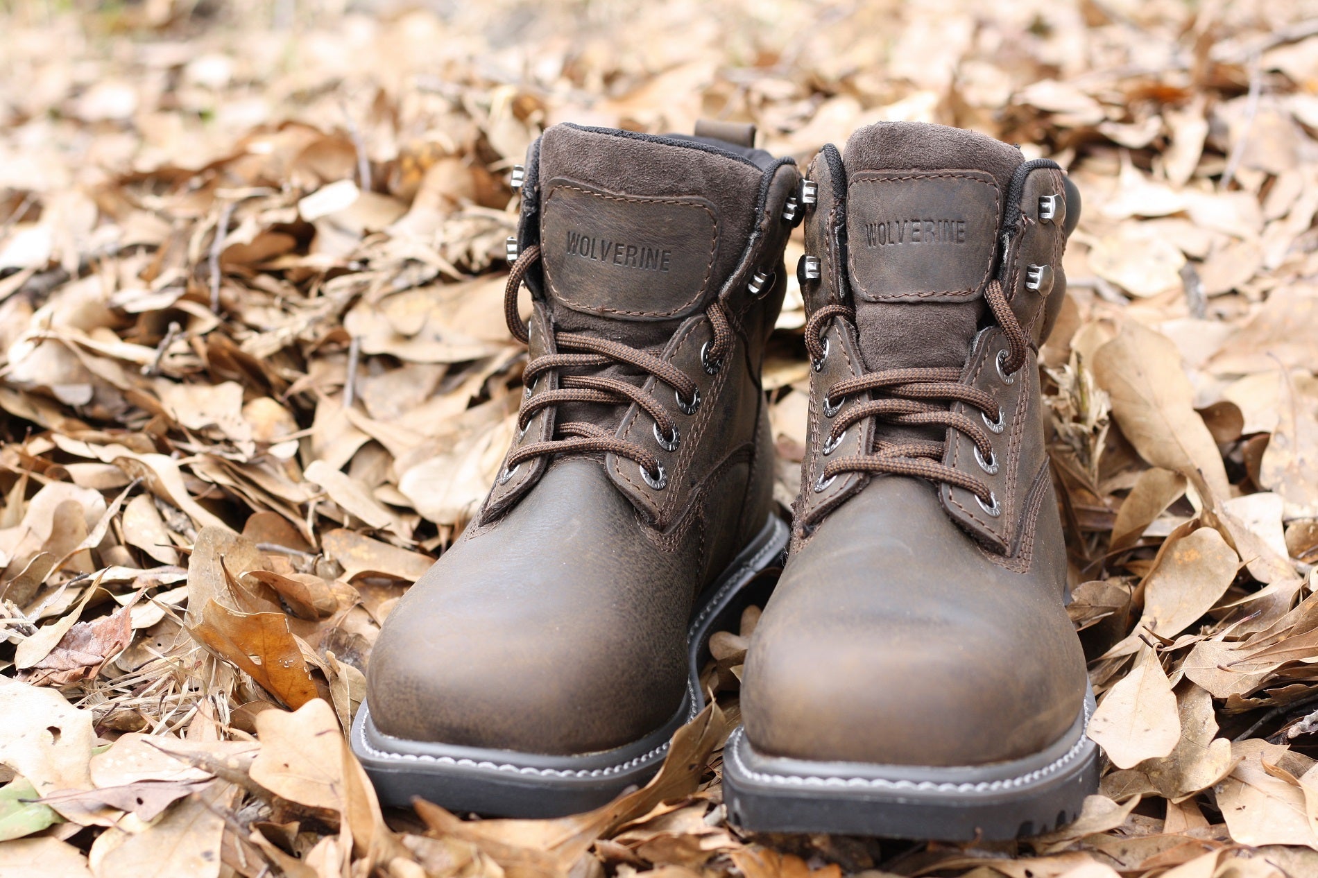 Close up of work boots on top of a bed of brown leaves