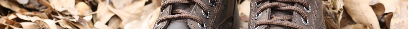 Close up of work boots on top of a bed of brown leaves